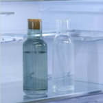 Close-up of two bottles on movable 1–2 trays inside a refrigerator, showing adjustable shelf height.